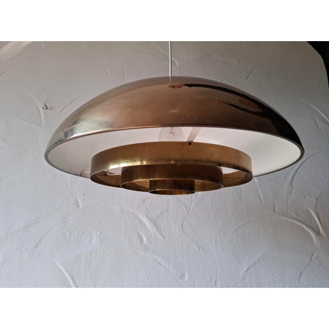 A beautiful brass ceiling light manufactured by Bergboms, Sweden, 1960s. The lamps have a light source surrounded by a...