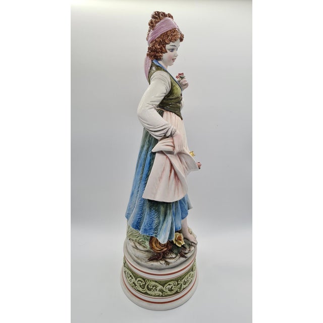 The ceramic figurine “Woman Gathering Flowers,” designed by Domenico Poloniato in Italy in the 1980s, is a decorative...