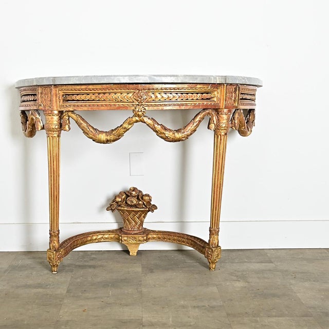 A dramatic 18th century Louis XVI period demilune-console from France, with an exquisite giltwood base supporting its...