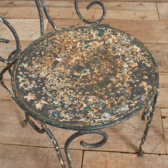 A beautiful pair of French black/green wrought iron garden armchairs. Each has decorative scrolled ironwork back and...