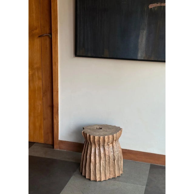 A striking sculptural side table crafted from solid teak wood, distinguished by its dramatic organic form and deeply...