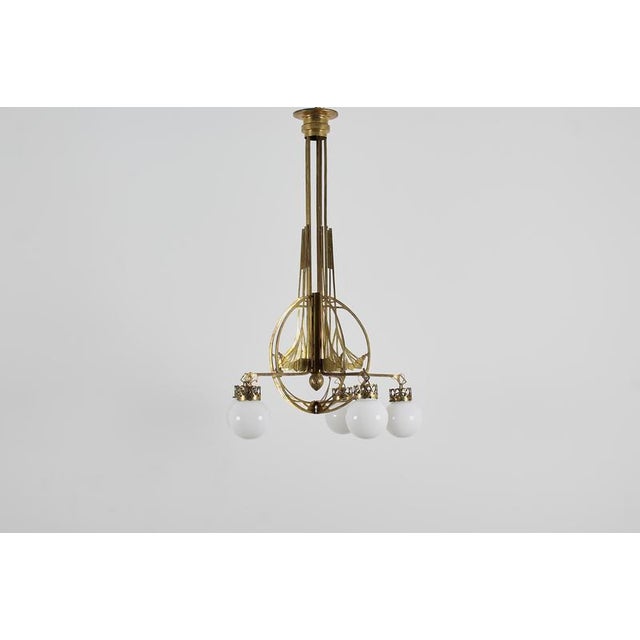An imposing five-arm Art Nouveau brass chandelier with extensive decorative friezes and milk glass globes. Made in Vienna,...