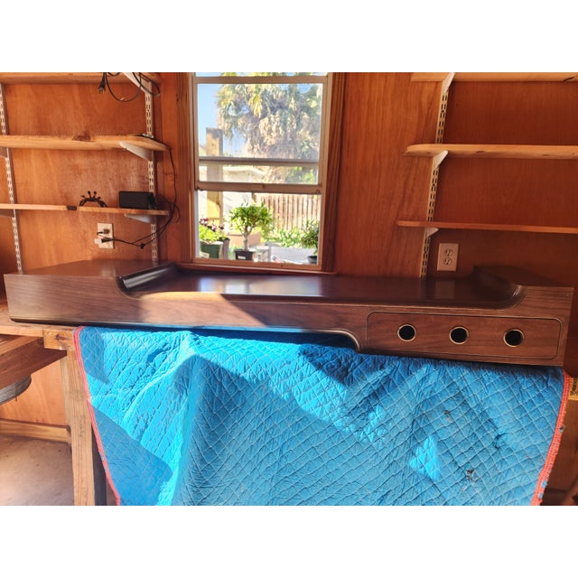 A custom walnut floating console by Lorin Marsh, featuring a clean, architectural silhouette with soft curved edges and...