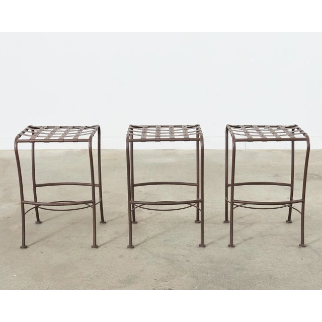 Handsome set of three wrought aluminum barstools featuring a neoclassical style lattice strap seat. Made in the midcentury...