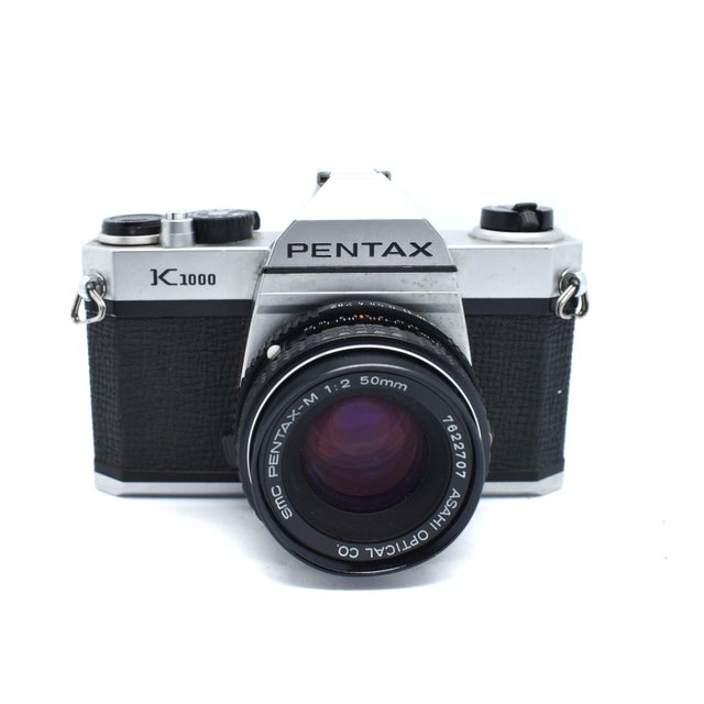 Bring a touch of mid-century analog charm to your shelves with this iconic Pentax K1000. Known as the "workhorse" of the...
