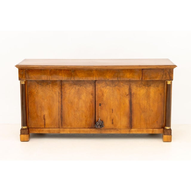 Italian Empire Walnut Commode a Vantaux, with three drawers above two cabinets between gilt metal and ebonized columns....