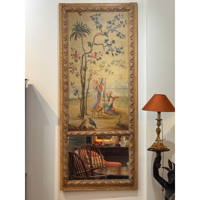 An 18th century French trumeau mirror, carved in pine with an inset oil on canvas chinoiserie scene depicting two figures...
