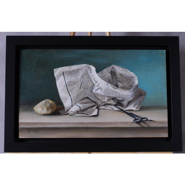 This oil on panel artwork presents a meticulously arranged still life featuring crumpled newspaper, a smooth stone, and a...