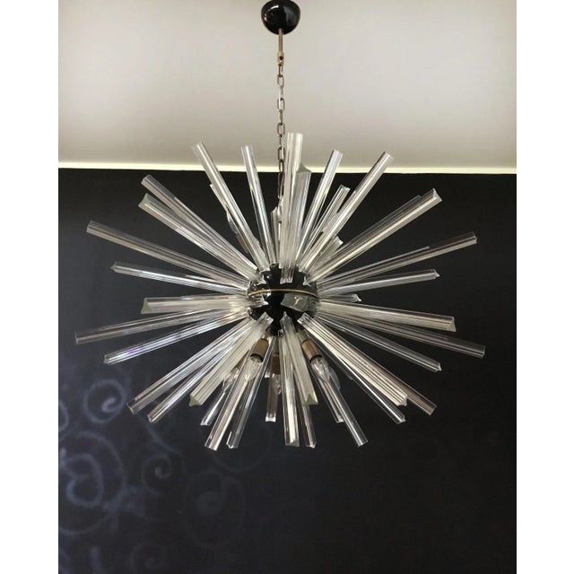 Sputnik chandelier from the 50s wtih crystal glass 'triedri' prisms radiating from the center black metal nucleus. It has...
