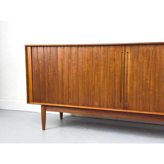 A stunning mid-century sideboard from the Johannes Aasbjerg manufactory, crafted from teak. The body is finished in teak...