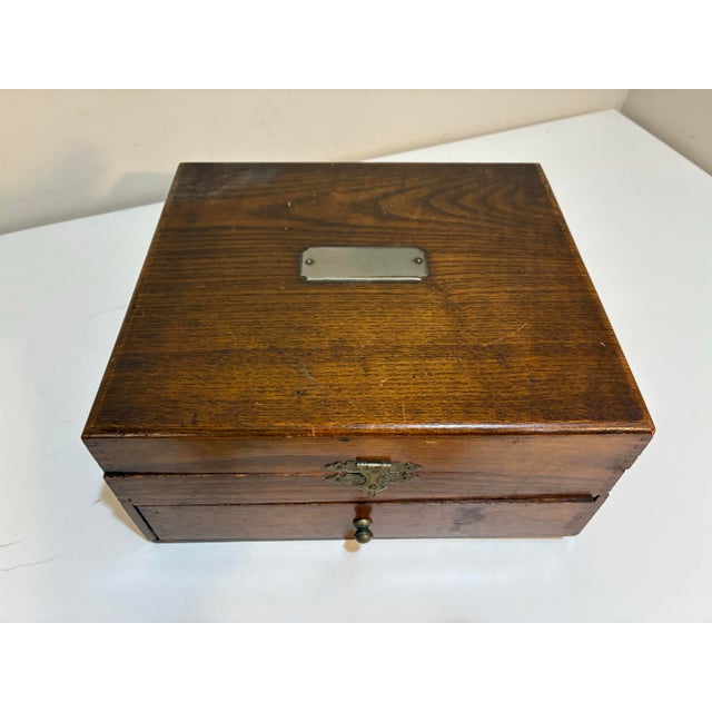 Wonderful antique wooden storage box dating to the early 20th century, featuring dovetailed construction, aged brass-tone...