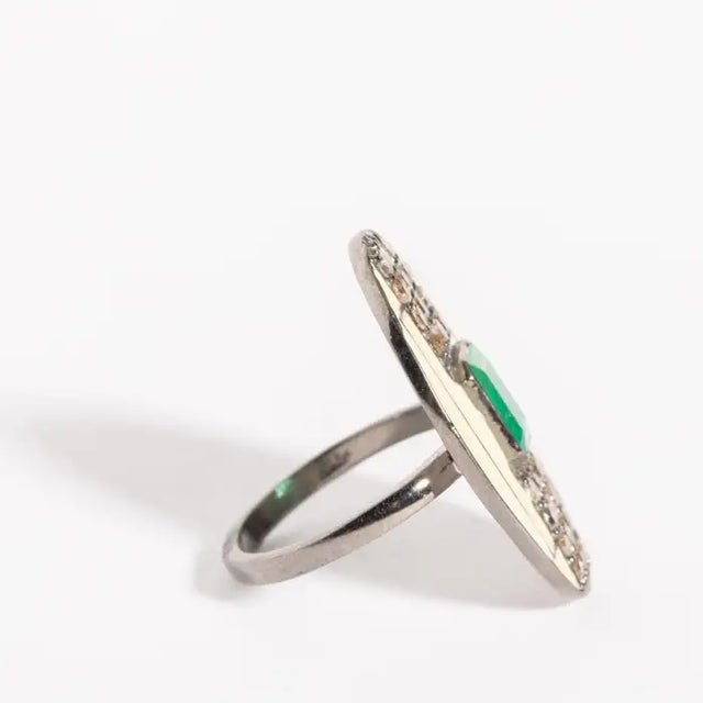 In an Art Deco design, a white enamel and sterling silver ring with an emerald-cut center stone emerald with brilliant-cut...