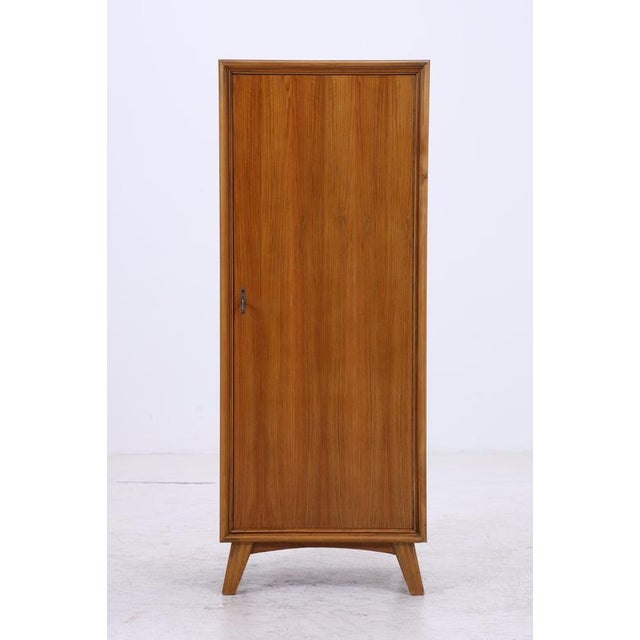 A narrow vintage wardrobe from the 1960s with a beautiful wood grain and clean proportions. The slightly splayed legs and...