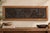 A courtyard gathering carved in high relief and finished in distressed black, with coppery wear on the raised surfaces. A...