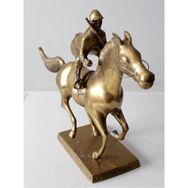 This vintage brass sculpture captures a horse and jockey in dynamic motion. The detailed craftsmanship and polished brass...