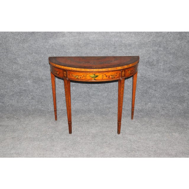 This elegant 19th century English Adams style demilune table showcases the refined artistry and timeless sophistication of...