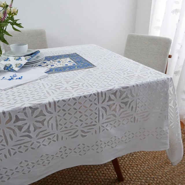 The Ester applique tablecloth highlights a sophisticated geometric design cut out in white cotton fabric and hand-sewn on...
