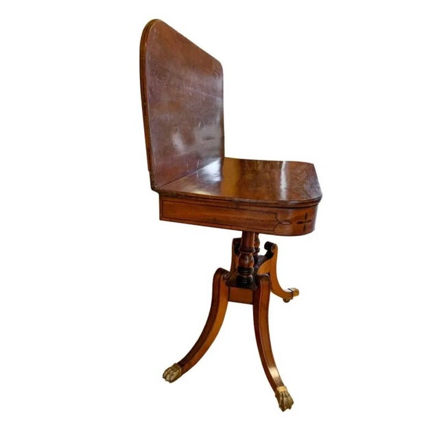 An English George III inlaid swivel-top card table Ebonized inlaid line and floral detailing Pedestal base Brass cuffed...