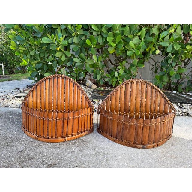 Distinctive vintage pair of sculptural wall baskets crafted from slender split bamboo slats, hand-bound with natural fiber...