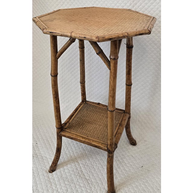 This vintage bamboo side table features an octagonal form with woven rattan surfaces on both the top and lower tier. The...