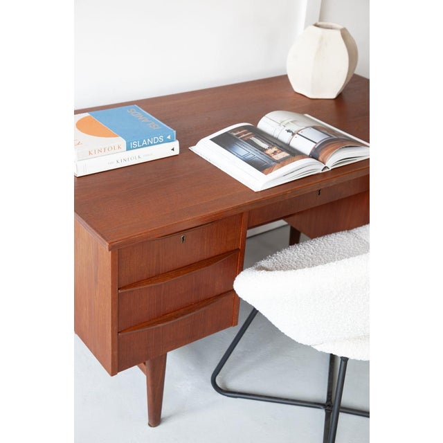 A handsome Danish executive desk in teak, standing on classically mid century rocket style legs. The desk has six deep...
