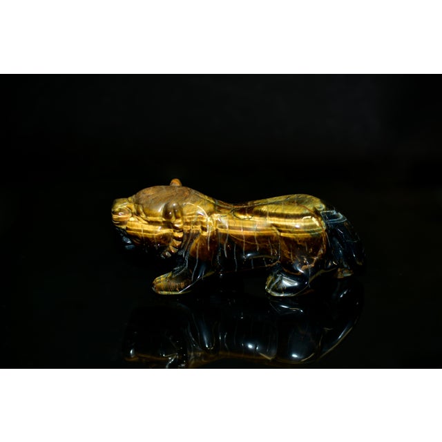 A hand-carved tiger sculpture rendered in natural Tiger’s Eye, showcasing the stone’s exceptional golden chatoyancy with...