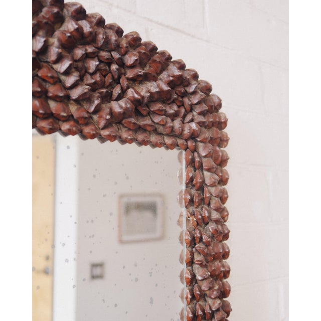 A wider format wall mirror with a dense pinecone frame, built from natural elements applied over a wood structure. The...