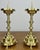 A striking pair of vintage brass candle holders featuring elegant turned stems, circular drip trays, and decorative claw...