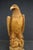 A large hand-carved pine sculpture depicting a bald eagle perched atop a stylized, saw-cut rock formation. Executed from a...