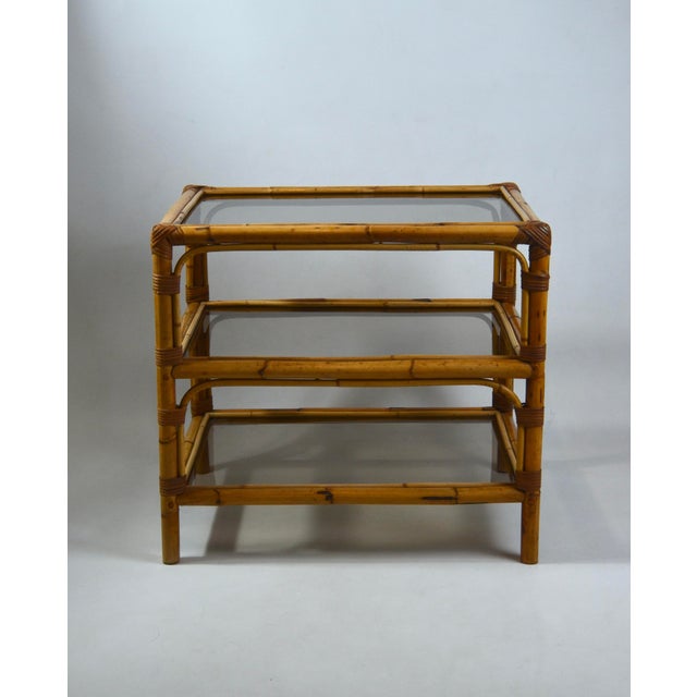 Elegant vintage three-tier side table crafted from bamboo with decorative rattan bindings and three lightly smoked glass...