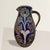 This early 20th-century German Handarbeit salt-glazed pitcher exudes whimsical charm and artisanal craftsmanship....