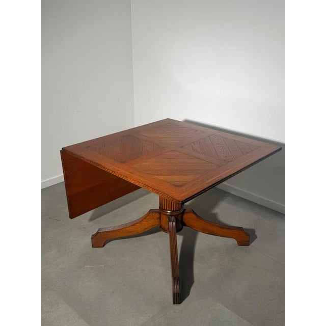 A beautifully crafted antique oak dining table featuring a striking parquet-style inlaid top and an elegant pedestal base....
