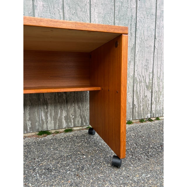 This compact Danish modern writing desk features pressed wood construction, teak veneer with original finish, and black...