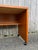 This compact Danish modern writing desk features pressed wood construction, teak veneer with original finish, and black...
