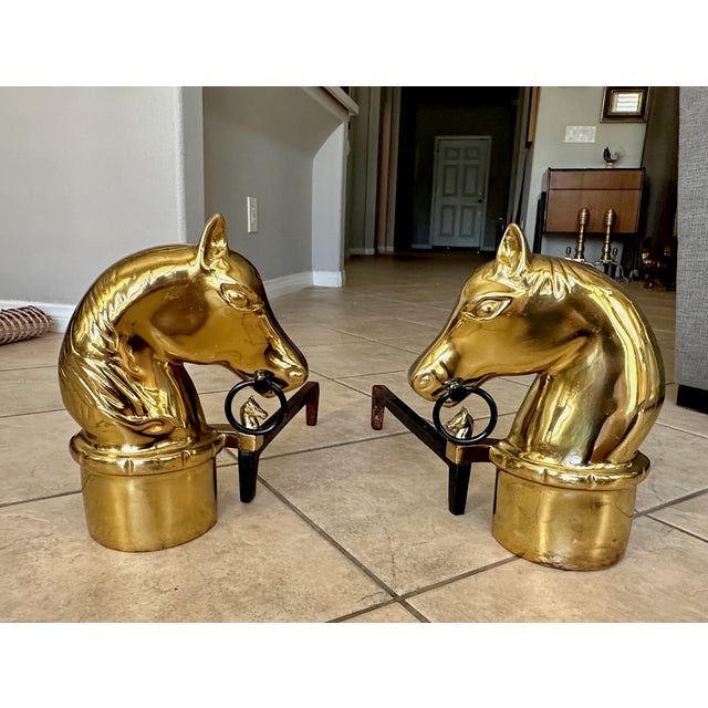 A very handsome pair of brass and cast iron andirons with a horse head motif, also features horse head finials on the...