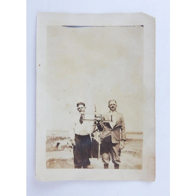 Antique early 20th century seipia tone photograph snapshot of two guys holding their model biplane. Looks like they are...