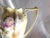 This is a pale yellow and white coffee pot with a very faded mark. It has a double handle design at the top, purple and...