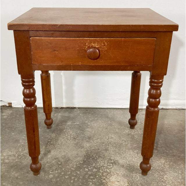 Antique Early American wood table with uniquely carved legs and single drawer finished with button knob. This sturdy piece...