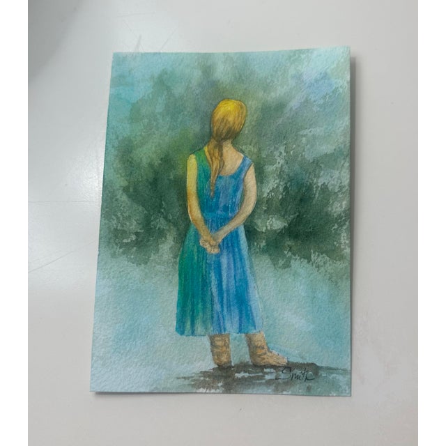 Serene and contemplative, After the Rain portrays a young woman standing quietly in a lush green landscape, hands gently...