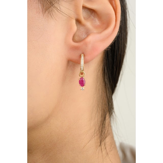 These elegant drop earrings feature dazzling oval-cut rubies and sparkling diamonds, beautifully set in 14k gold hoops....