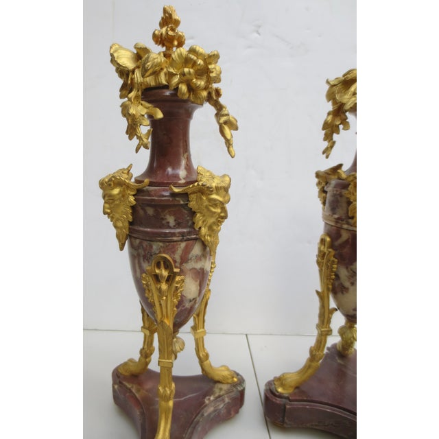 Gilt Bronze floral ornaments on a fine rouge marble urn. Tripod feet with gilt legs carry the marble urn upward, topped by...