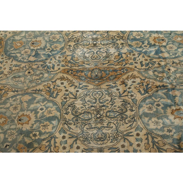 An early 20th century Persian Kirman rugs, the camel field with floral sprays around gray and rust medallions containing...