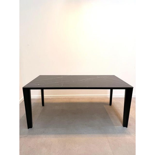 sleek and contemporary dining table featuring a premium black ceramic tabletop with elegant white marble-effect veining....
