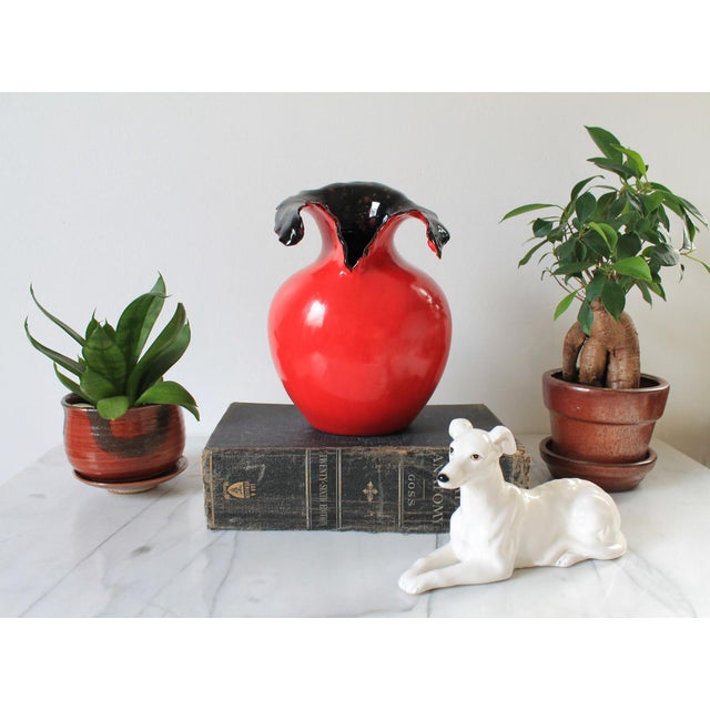 Vintage artisan made ceramic red vase with speckled black interior. Signed by artist on bottom. One flea bite chip. Pictured.