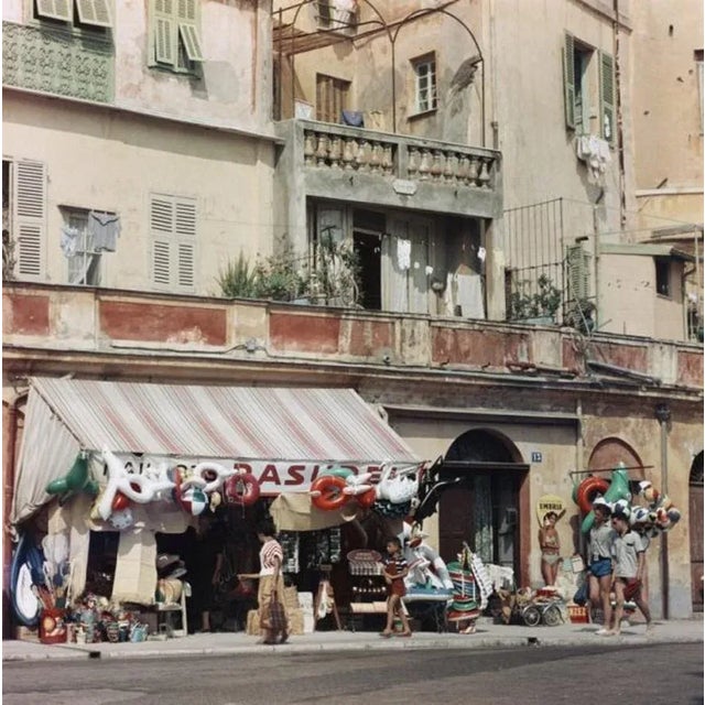 Menton 1957 by Slim Aarons Slim Aarons Limited Estate Edition A shop selling beach paraphernalia in Menton, in...