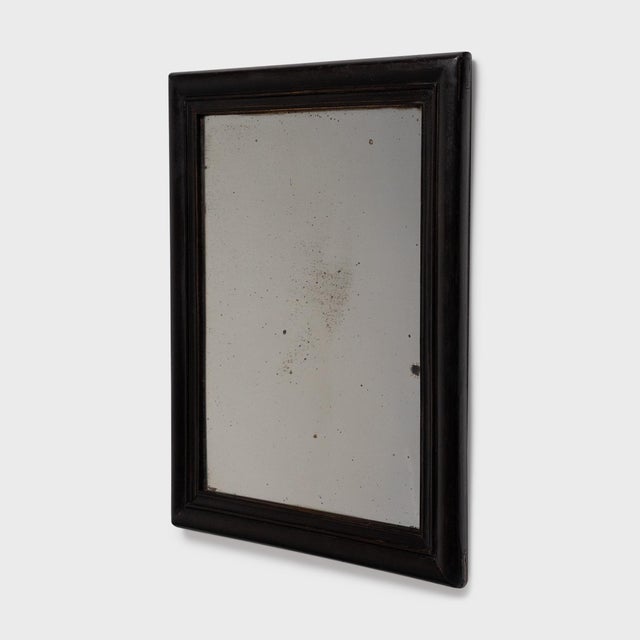 This antique Chinese mirror dates to the early 20th century and has a simple rectangular frame with beveled molding and...