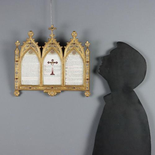 A gilded bronze altarpiece in neo-Gothic style with engravings and small enameled flowers. The frame features blue and red...