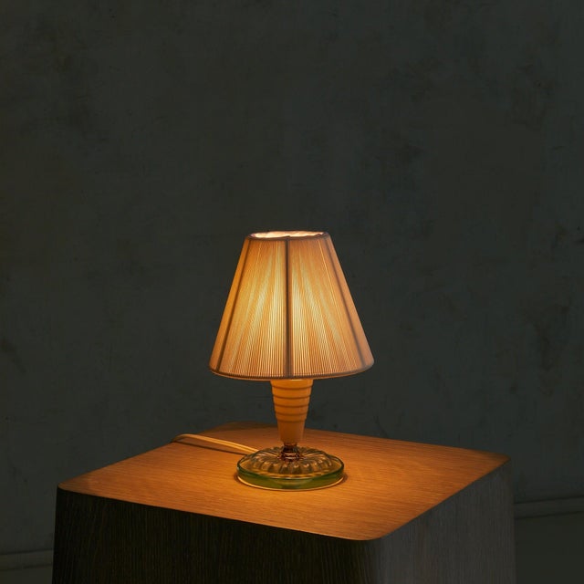 A petite Italian table lamp from the 1950s, standing just 9 inches tall. The ivory-lacquered metal stem rises from a...