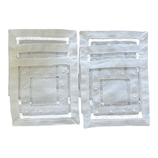 An elegant set of six new, unused white cocktail napkins featuring hand embroidery and two concentric squares of openwork...