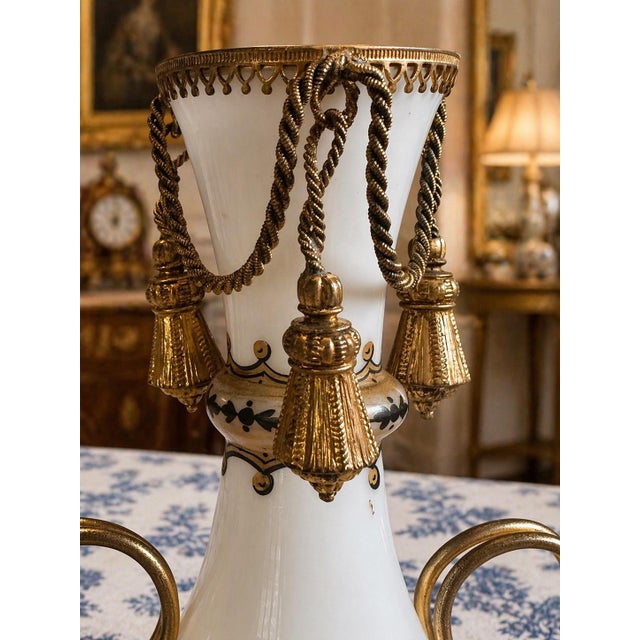 Elegant antique French white opaline vase mounted in an ornate gilt bronze stand with richly detailed tassel...